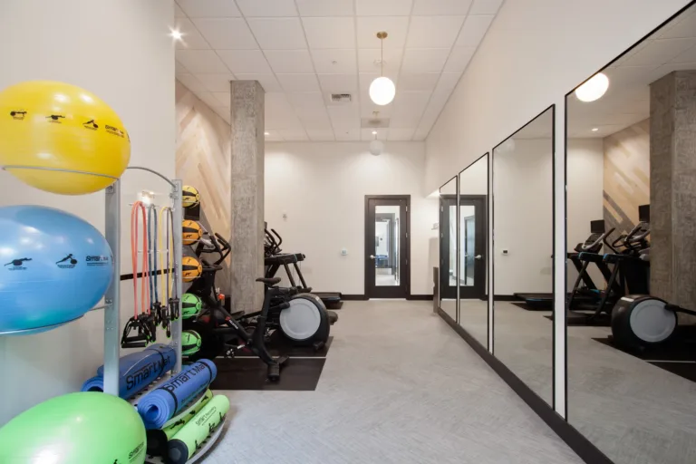 A well-equipped gym with exercise balls, mirrors, and cardio machines. Neatly organized equipment and modern interior design create an inviting workout environment.