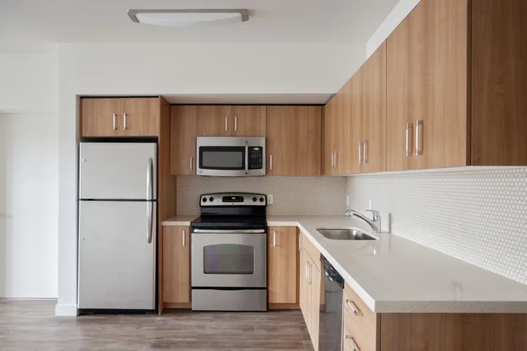 Modern kitchen in an apartment featuring stainless steel appliances and wooden cabinets.