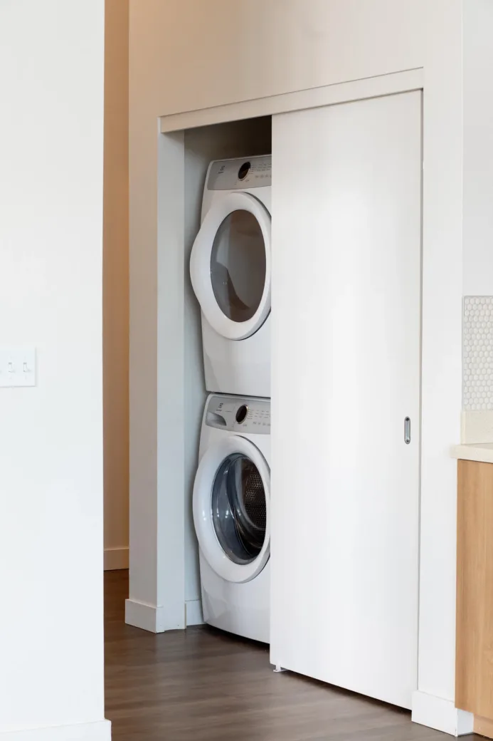 Apartment laundry area with a stacked washer and dryer set behind a sliding door.