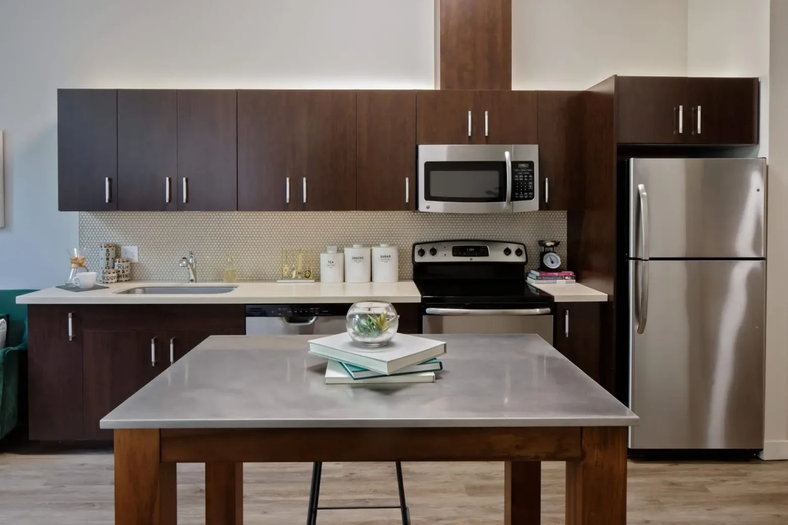Modern kitchen with dark wood cabinets, stainless steel appliances, including a microwave and refrigerator, and a central island with a polished countertop.